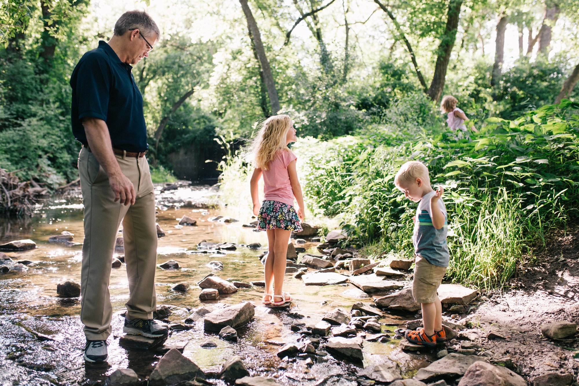 Grandfather plays in the creek with his grandchildren.