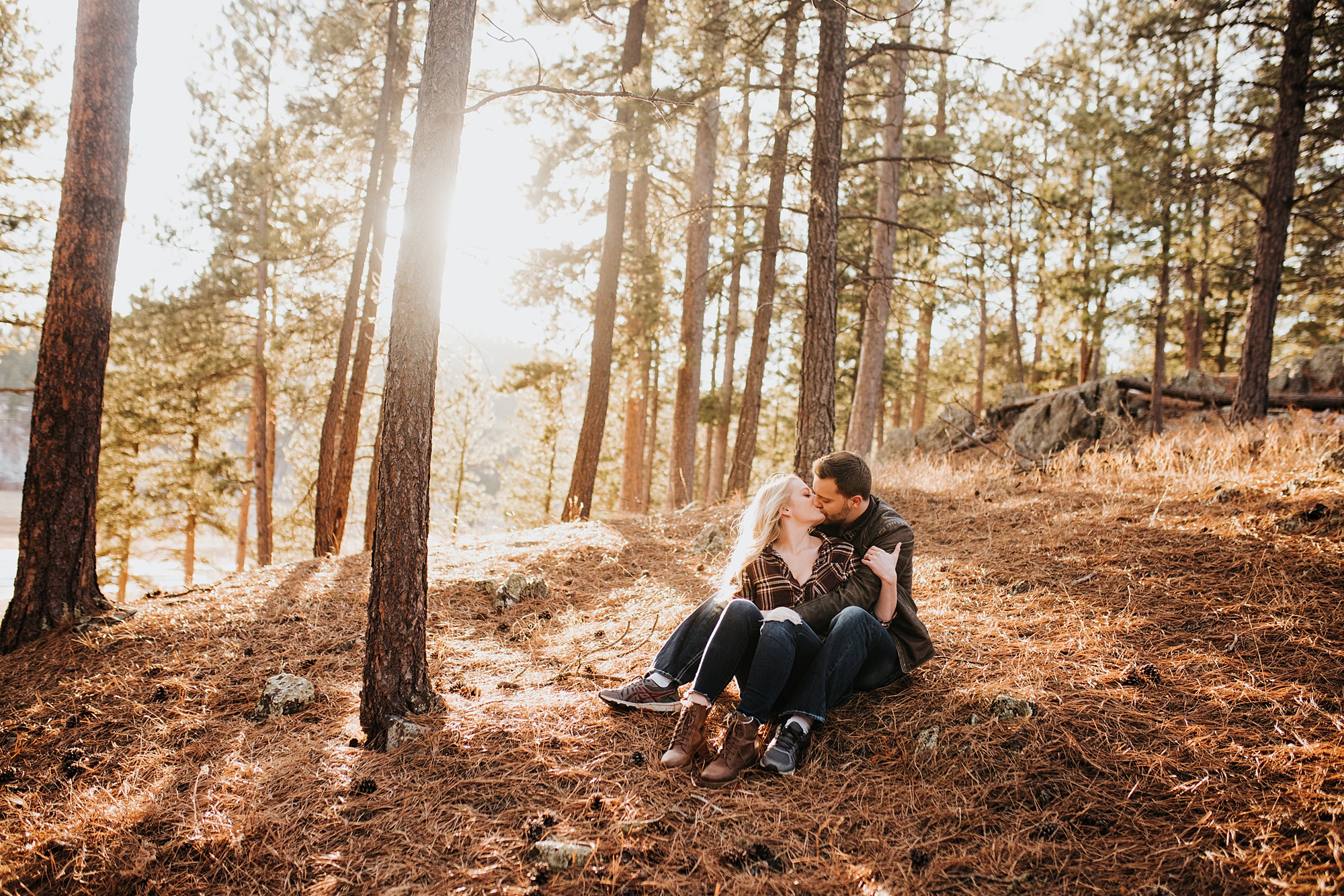 couple sitting in the woods for their engagement session.